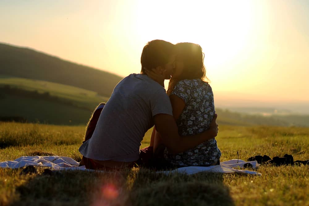 un homme et une femme s'assoient sur l'herbe et s'embrassent