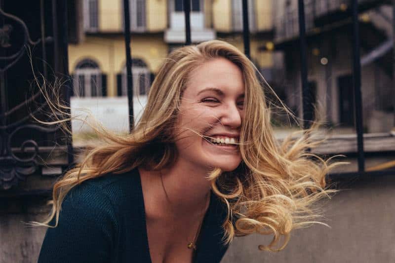 une blonde souriante les yeux fermés