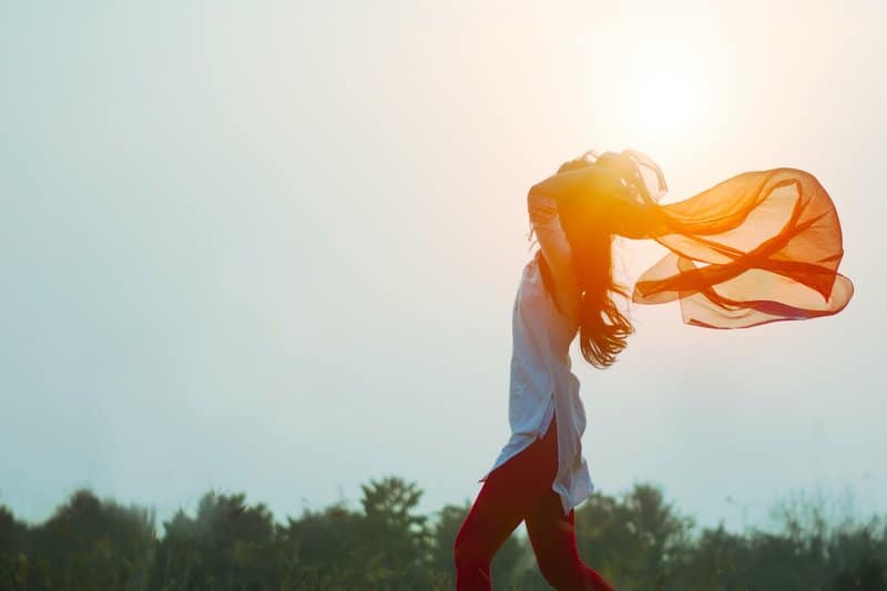 une femme marche à travers un champ avec un foulard rouge