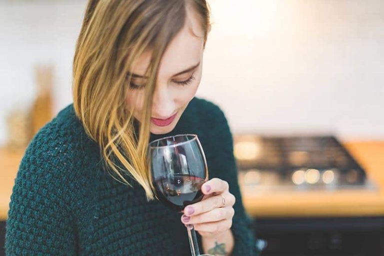 une femme brune tenant un verre de vin