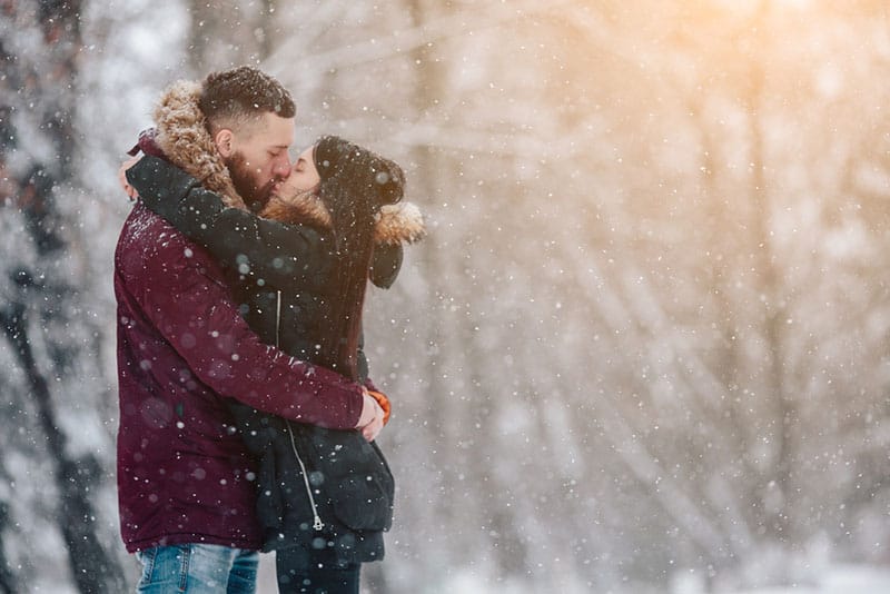 jeune couple s'embrassant sur la neige dans la nature