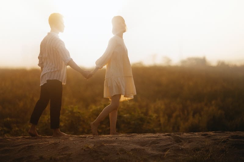 un homme et une femme se tenant la main marchant pieds nus