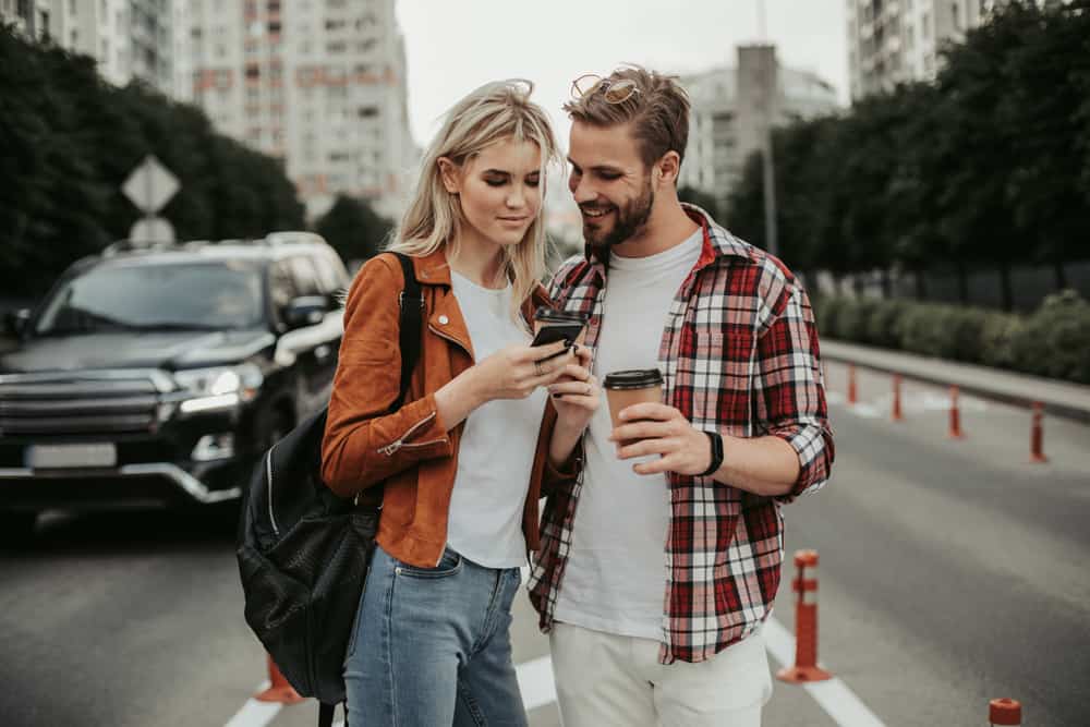 un homme et une femme sont debout avec un téléphone à la main