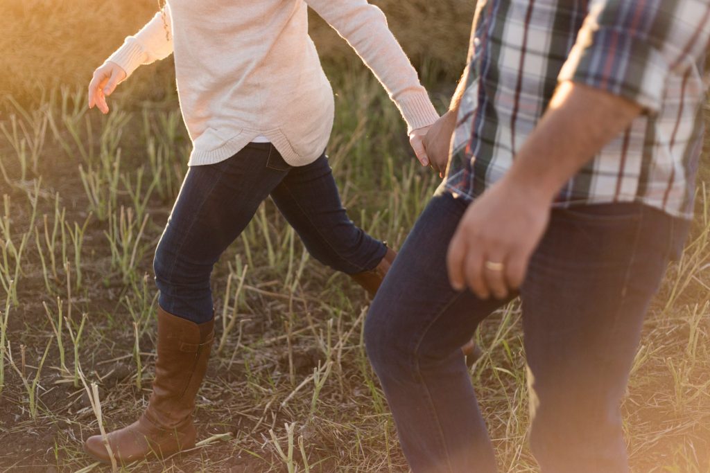 un homme et une femme traversent le champ en se tenant la main