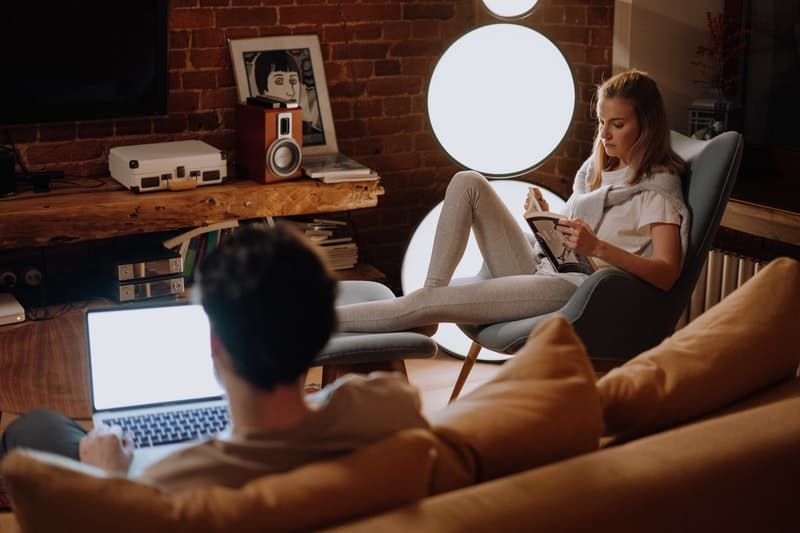 un homme sur un ordinateur portable pendant qu'une femme lit un livre