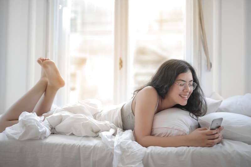 une femme avec un téléphone à la main au lit