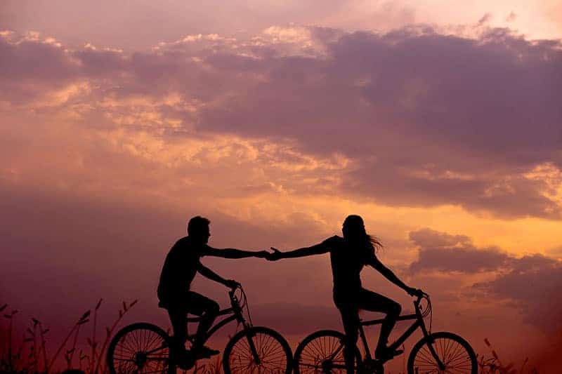 un homme et une femme font du vélo et se tiennent la main