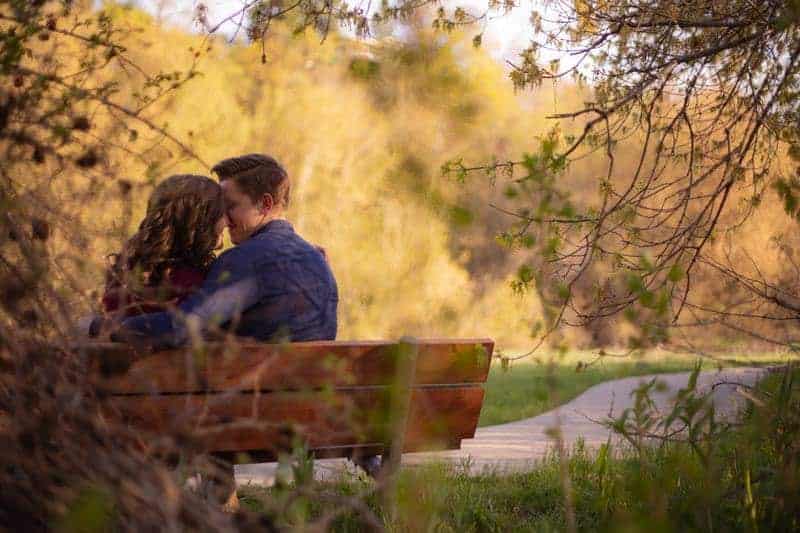 un homme et une femme s'assoient sur un banc et s'embrassent