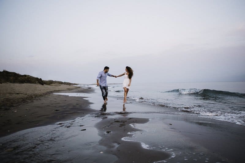 un homme et une femme marchent le long du bord de mer