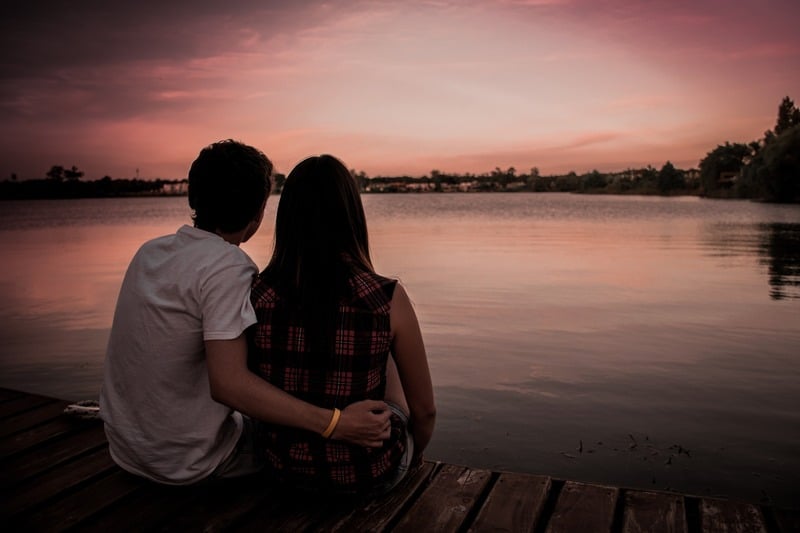 un homme et une femme sont assis au bord du lac