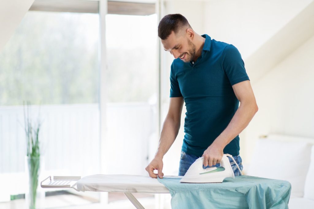 un homme repasse une chemise