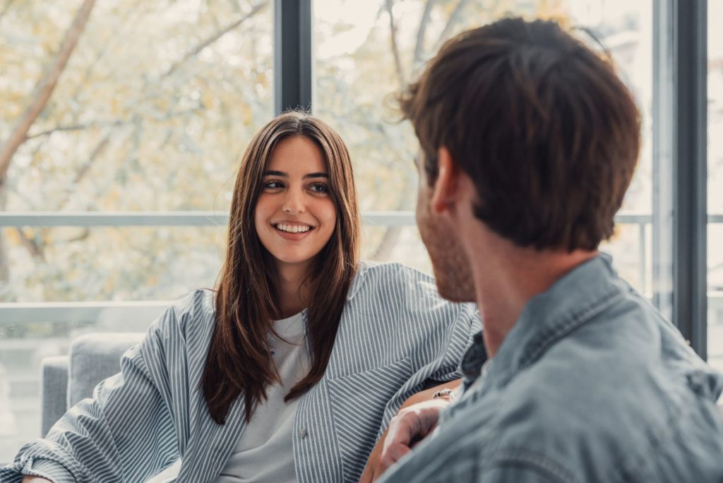 une fille souriante aux cheveux bruns parle à un homme