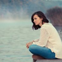 femme assise seule au bord du lac