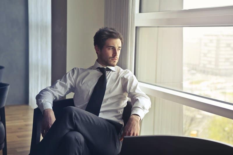 le gars s'assoit et regarde pensivement par la fenêtre