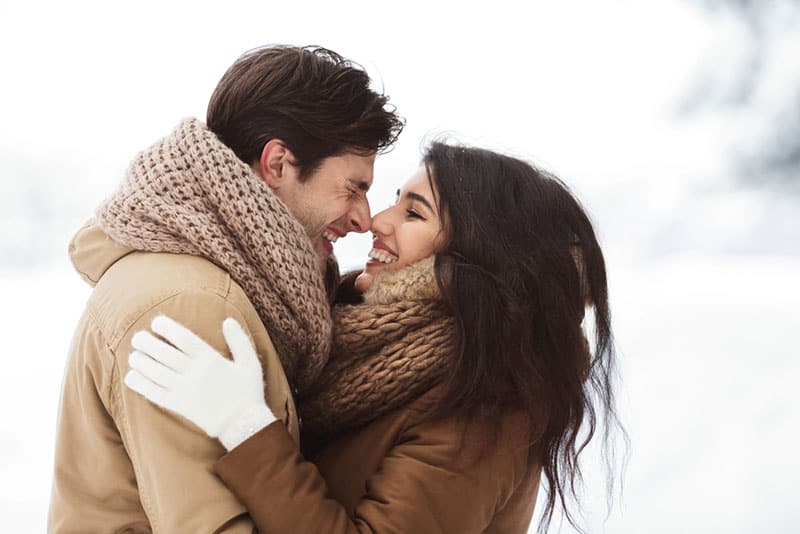 heureux jeune couple caresses en hiver dans la neige