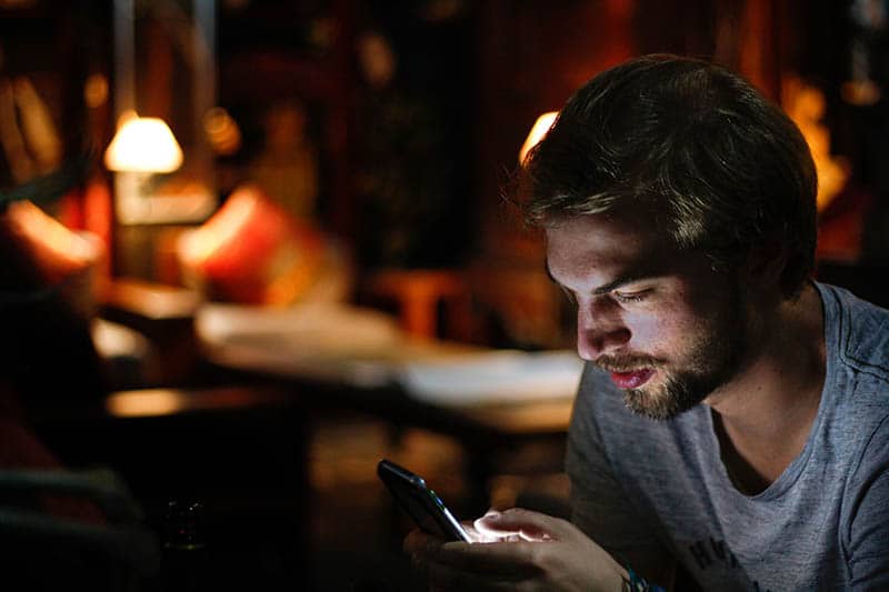 jeune homme textos dans l'obscurité