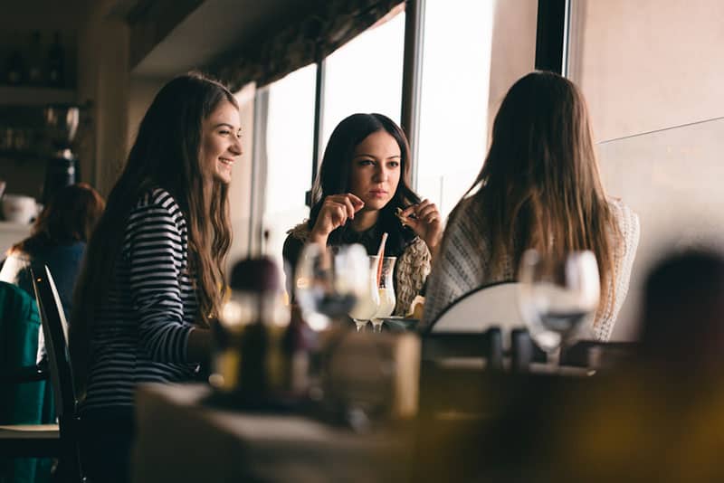 les trois filles sont assises à la table en train de déjeuner et de parler