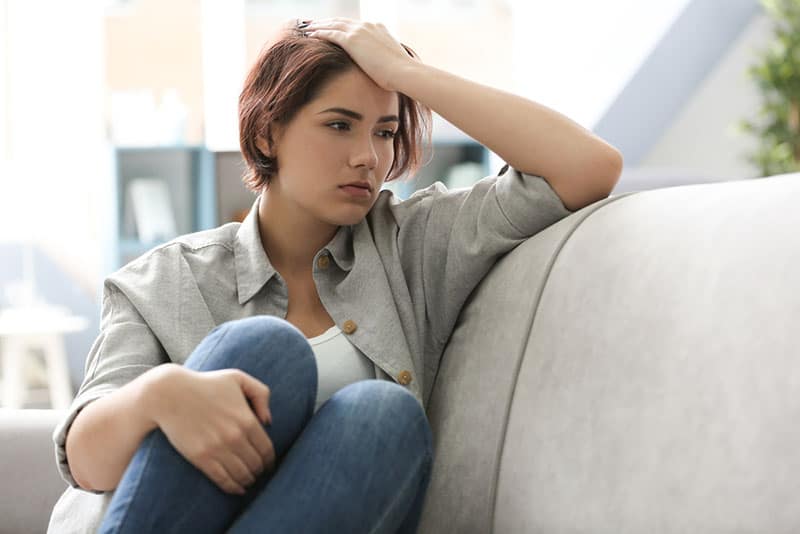 triste et déprimé jeune femme assise sur un canapé