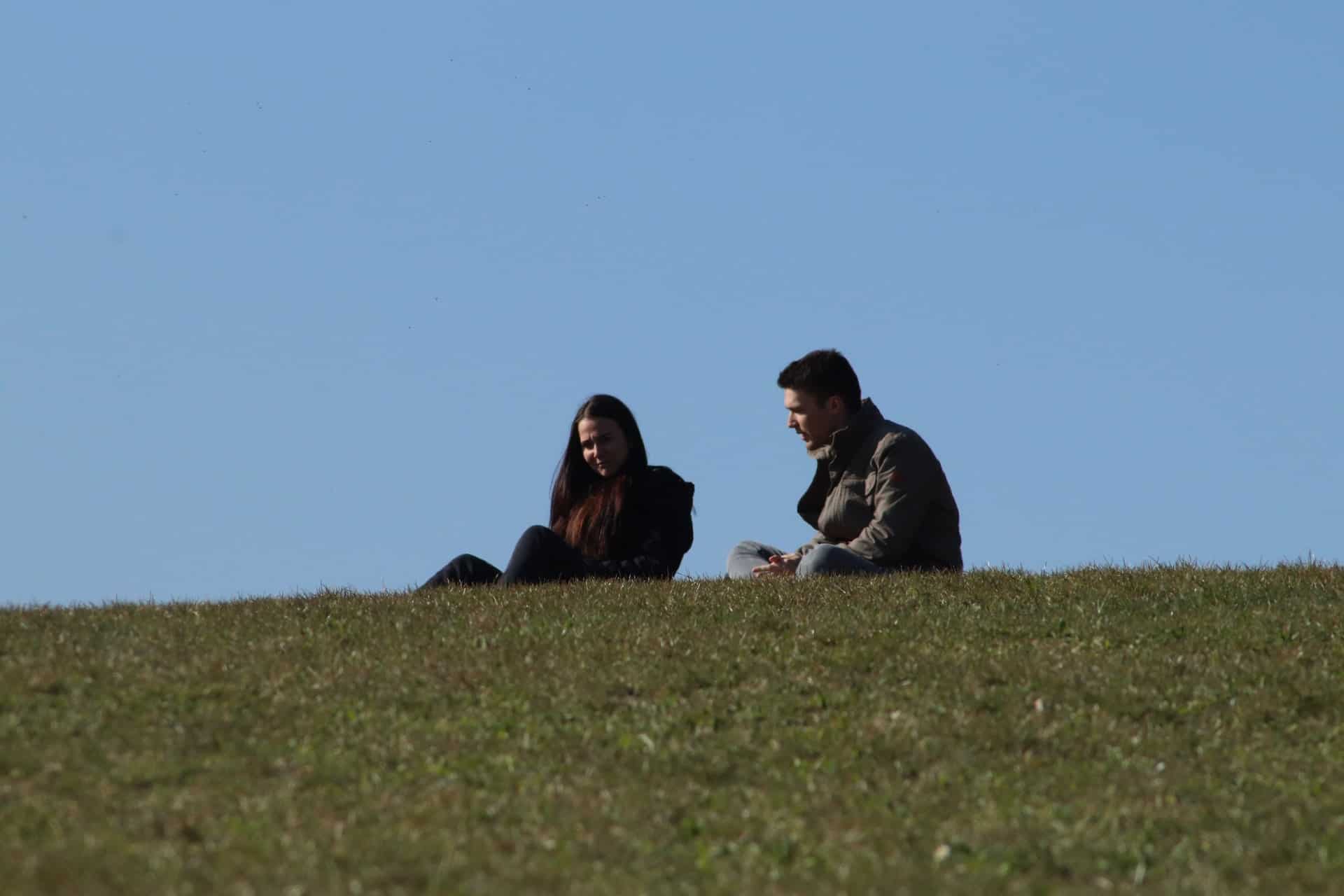 un homme et une femme s'assoient sur l'herbe et parlent