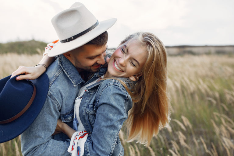 un homme et une femme s'embrassent debout dans un champ