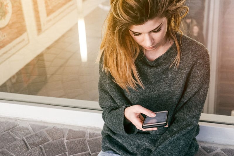 femme blonde avec téléphone texto