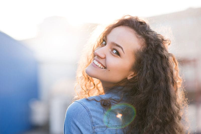 heureuse jeune femme aux cheveux bouclés regardant en arrière