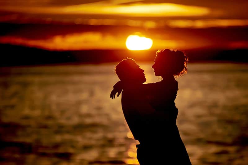 silhouette, jeune, couple, étreindre, Coucher soleil