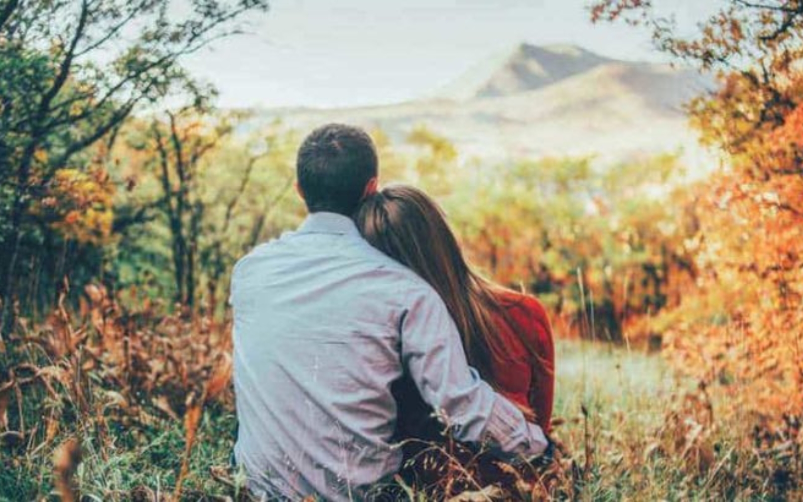 une femme et un homme embrassent assis sur lherbe