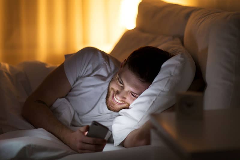 homme, rire téléphone, dans lit