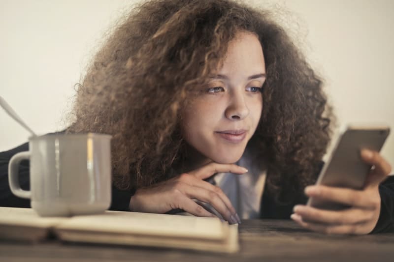 jolie femme bouclée en regardant le téléphone