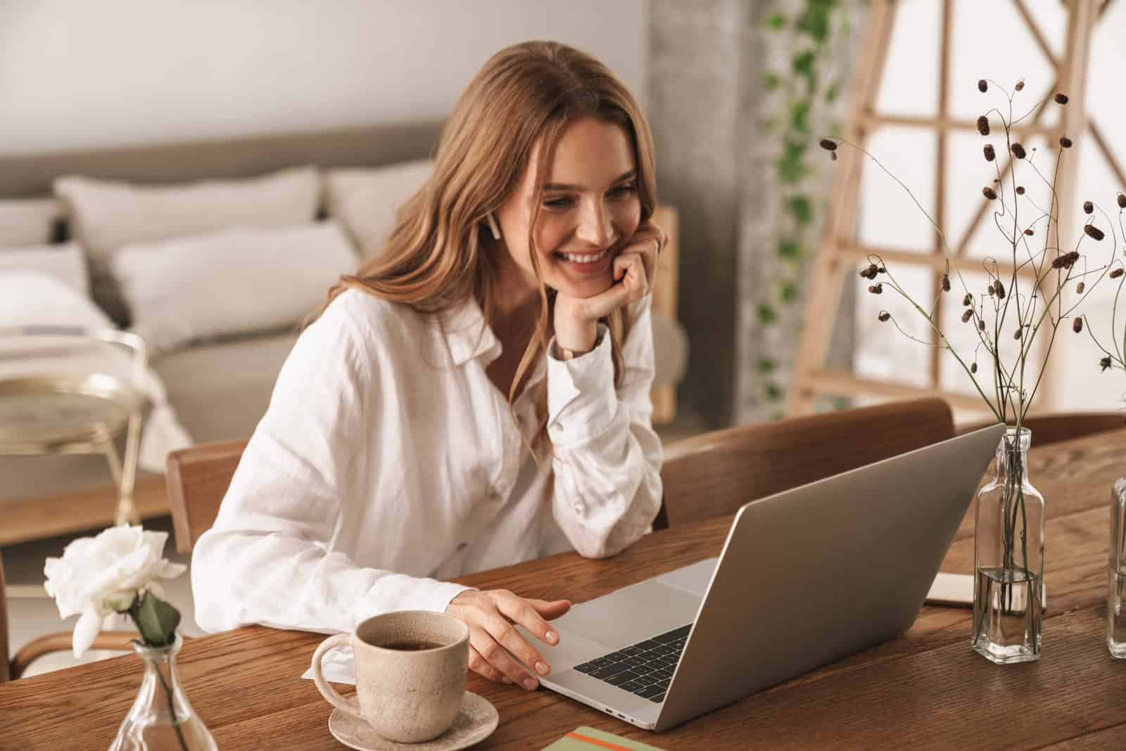 une femme aux cheveux bruns souriante assise derrière un ordinateur portable