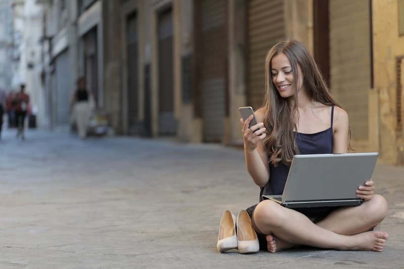 une femme souriante assise sur le béton