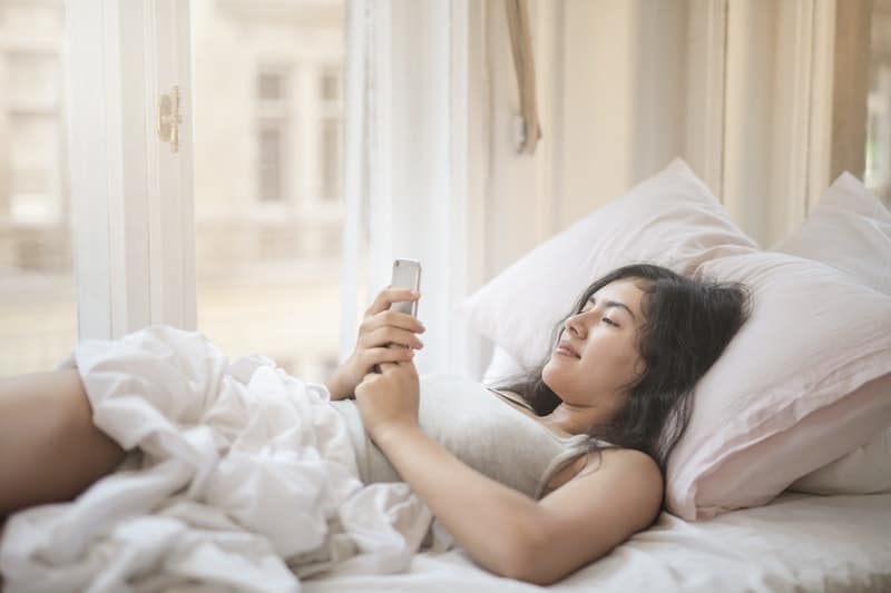 une femme souriante regarde le téléphone