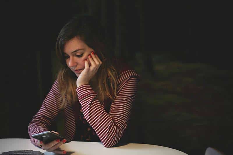 une femme triste regarde son téléphone portable