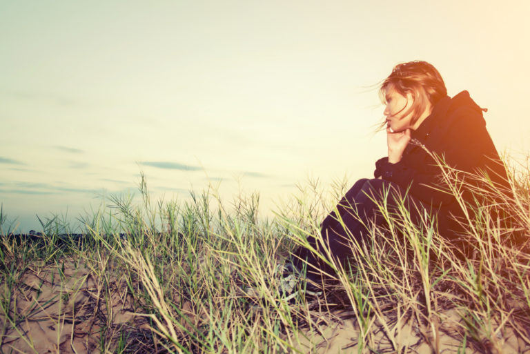 une femme triste assise sur l'herbe