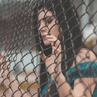 la femme regarde à travers la clôture