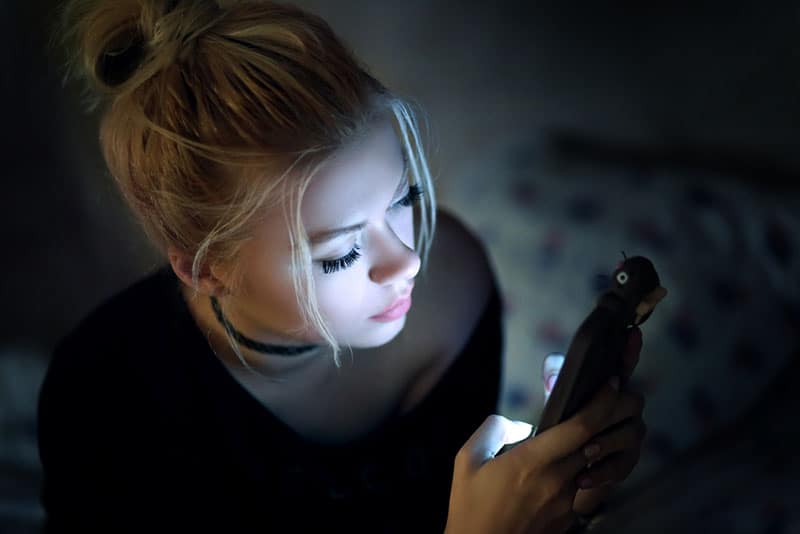 blonde jeune femme au téléphone dans l'obscurité