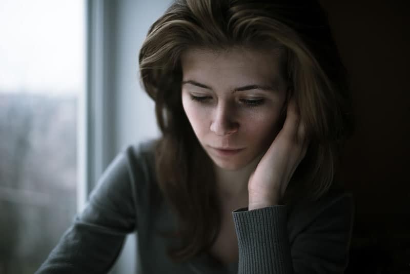 femme blonde déprimée par fenêtre