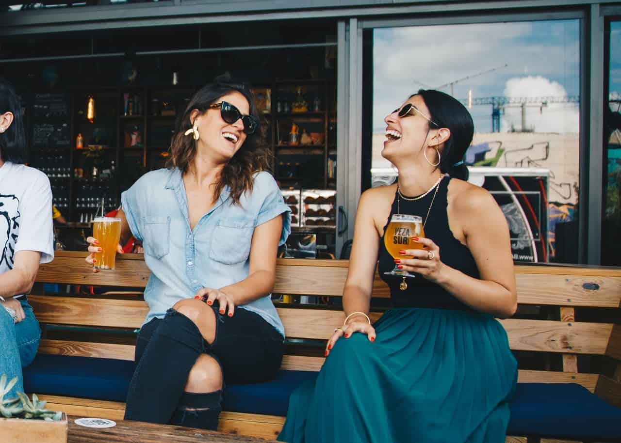 la femme est assise en riant et en buvant de la bière
