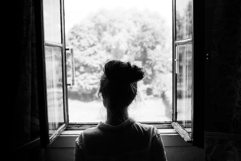 triste jeune femme regardant par la fenêtre