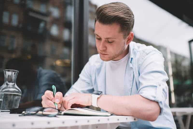 un homme est assis et écrit dans un journal
