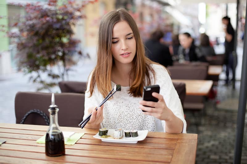 une femme assise mange un pieu et écrit un message