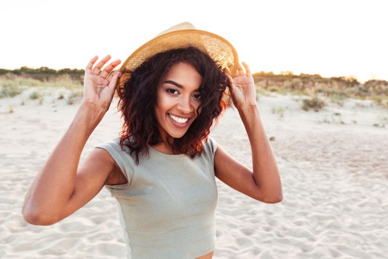 heureuse femme noire avec un chapeau à la plage