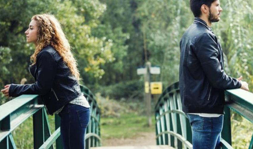 couple triste debout sur le pont au milieu du bois