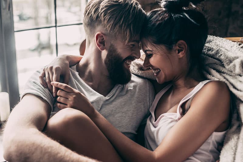 joli jeune couple câlins près de la fenêtre
