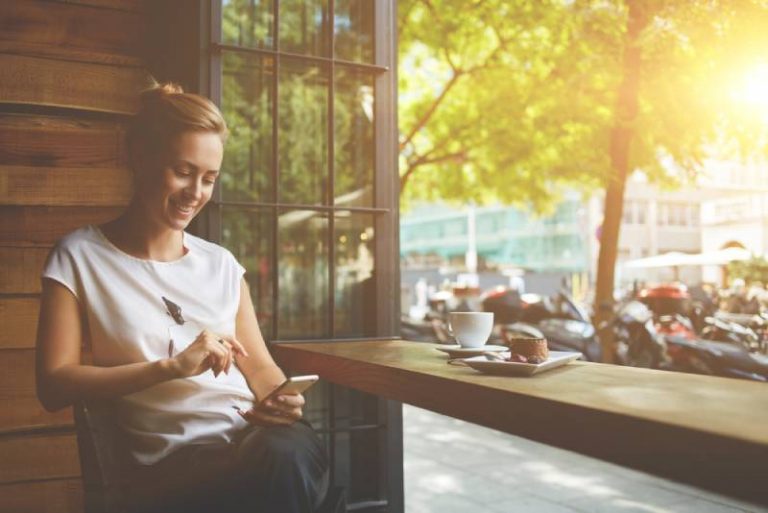 femme heureuse au bar à café en regardant son téléphone