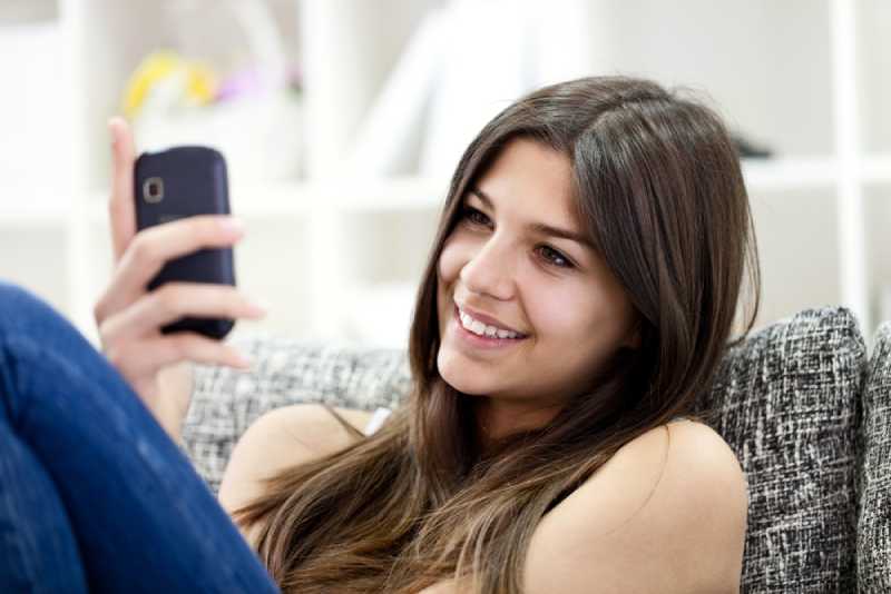 Adorable fille souriant et lisant un message au téléphone