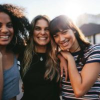 Trois jeunes filles souriantes posent à l'extérieur