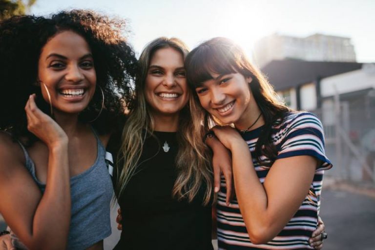 Trois jeunes filles souriantes posent à l'extérieur