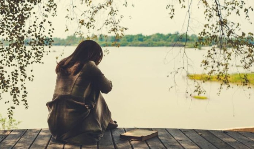 triste femme assise au bord du lac